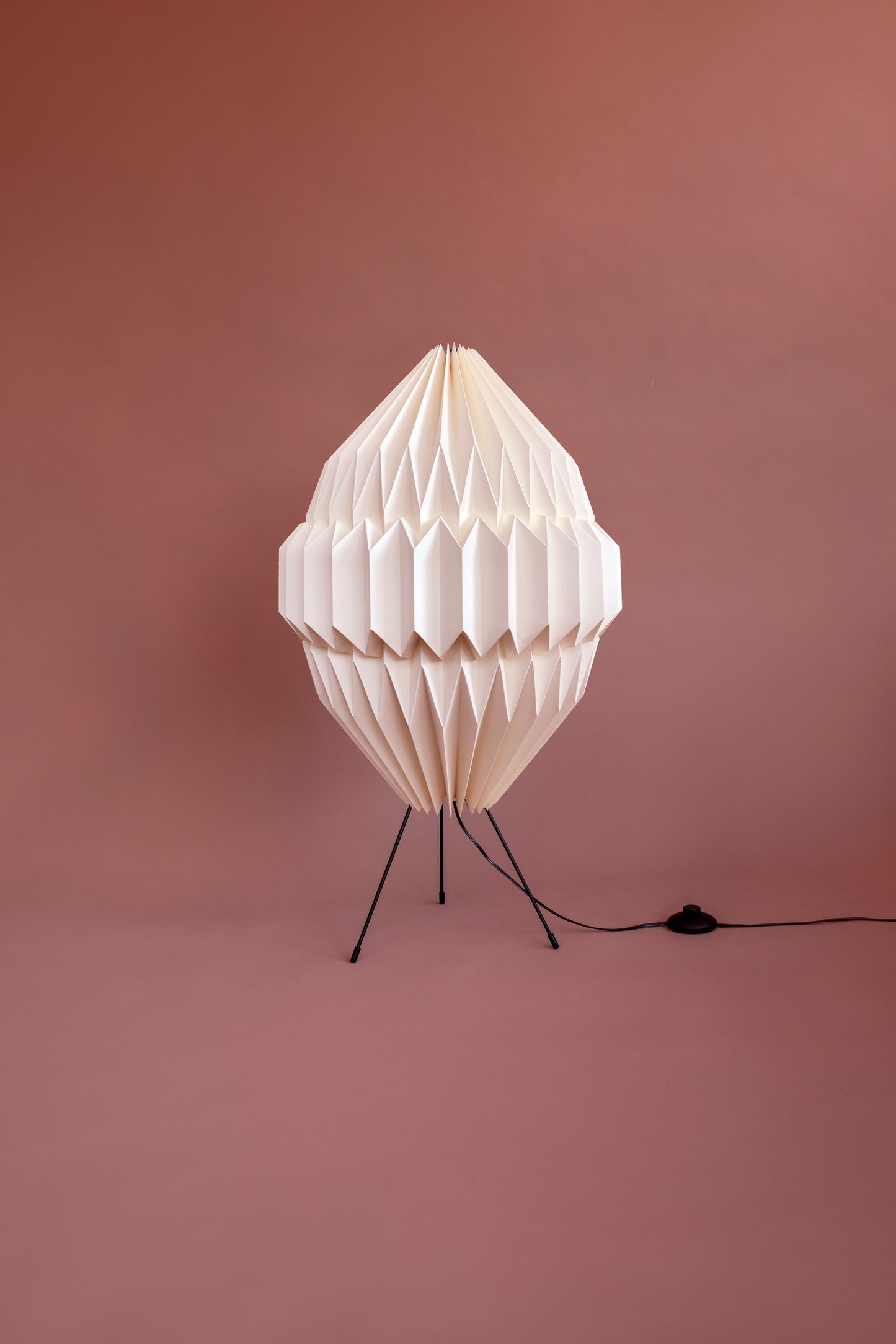 Plié Lights, lámpara de piso altura baja referencia Aries, hecha a mano, caperuza hecha en papel plegado a mano. Soporte metálica y cable transparente. Acabado blanco. Producto hecho en Colombia. Diseño Colombiano. igura geométrica muy interesante. Ideal para iluminar y darle calidez a los espacios.