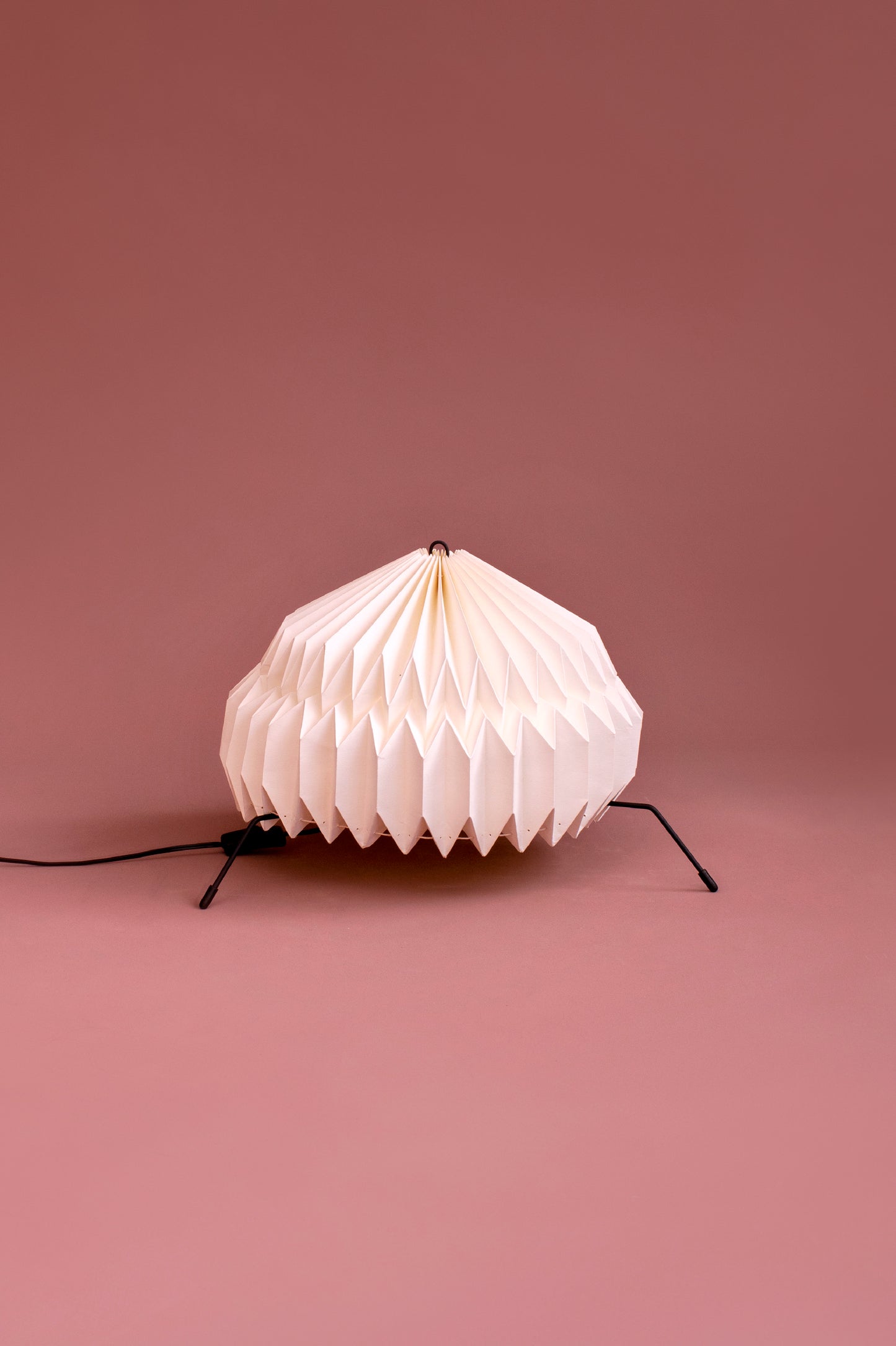 Lámparas Plié referencia Atria fabricada con base metálica y caperuza hecha en papel plegado. Perfecta para iluminar espacios y dar un brillo a los espacios. Lámpara de mesa o lámpara de piso