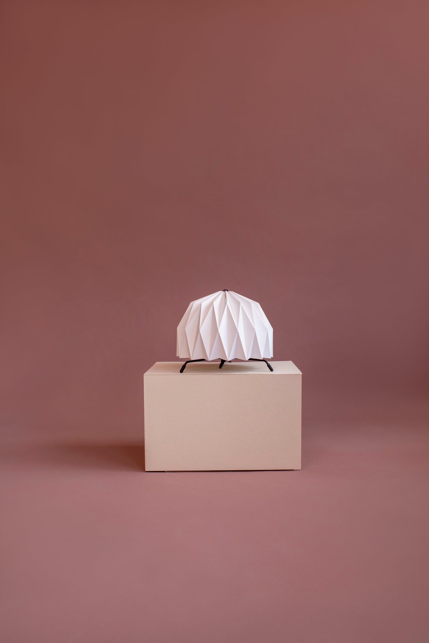 Lámpara de mesa marca Plié, Fenix fabricada con base metálica y caperuza hecha en papel plegado. Perfecta para iluminar espacios pequeños y dar un brillo a los espacios. Una lámpara es de tamaño mediano y las otras dos lámparas son chiquitas, perfectas para espacios pequeños, mesa de noche o en la biblioteca. Diseño Colombiano, hecho a mano en colombia.
