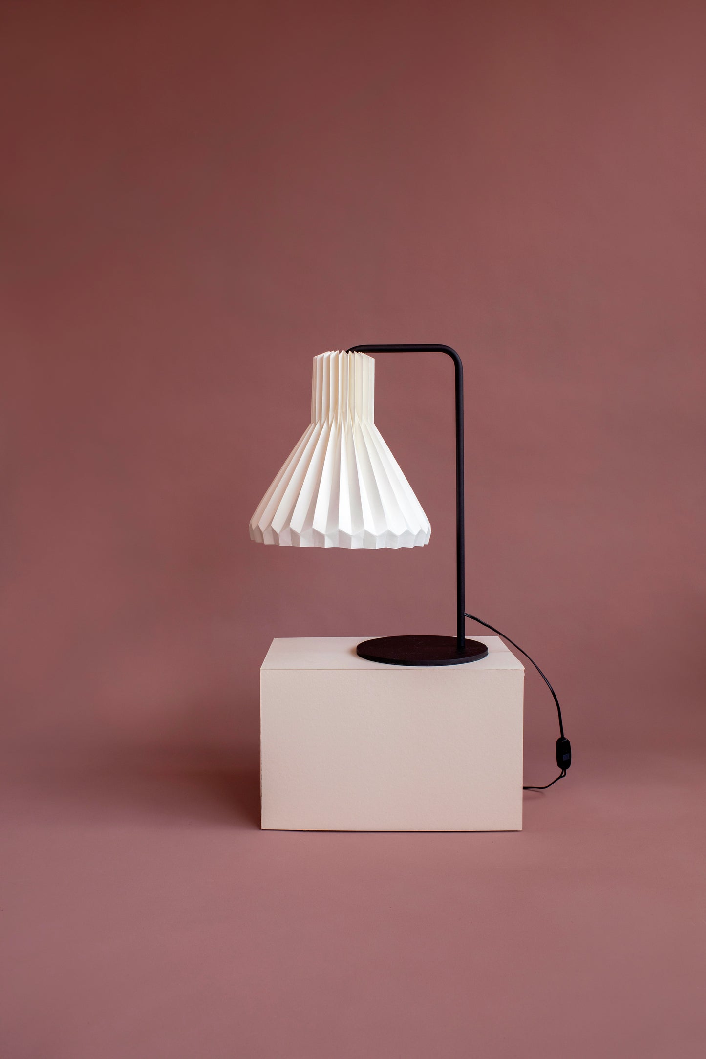 Lámpara de mesa marca Plié, referencia Lyra. Fabricada con base metálica y caperuza hecha en papel plegado. Ideal para iluminar y ambientar espacios cálidos. Funciona para mesa de noche. Diseño colombiano. Hecha a mano en Colombia.