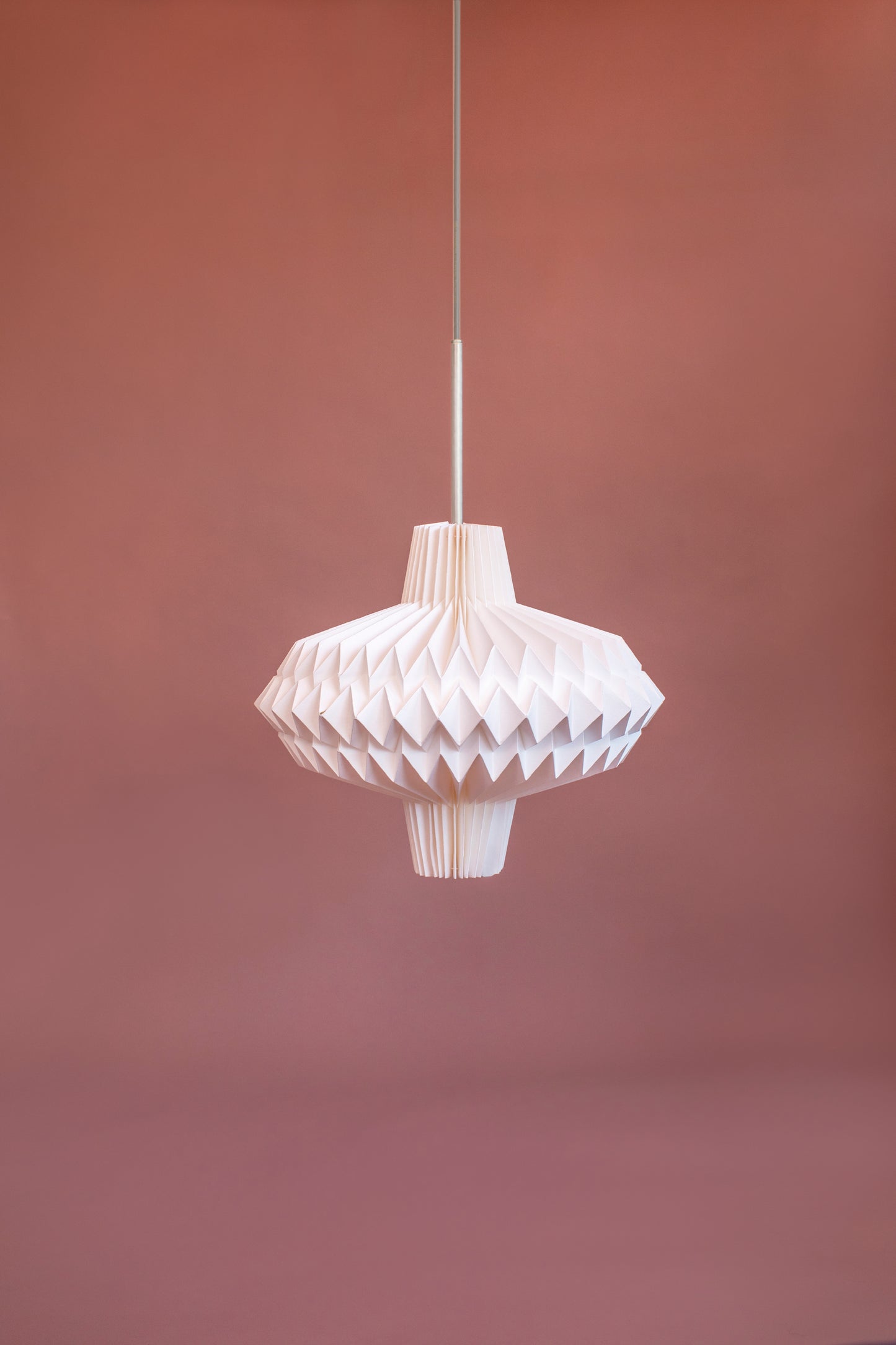 Lámpara Colgante marca Plié, referencia Antares fabricada con papel plegado. Base metálica blanca con cable transparente.