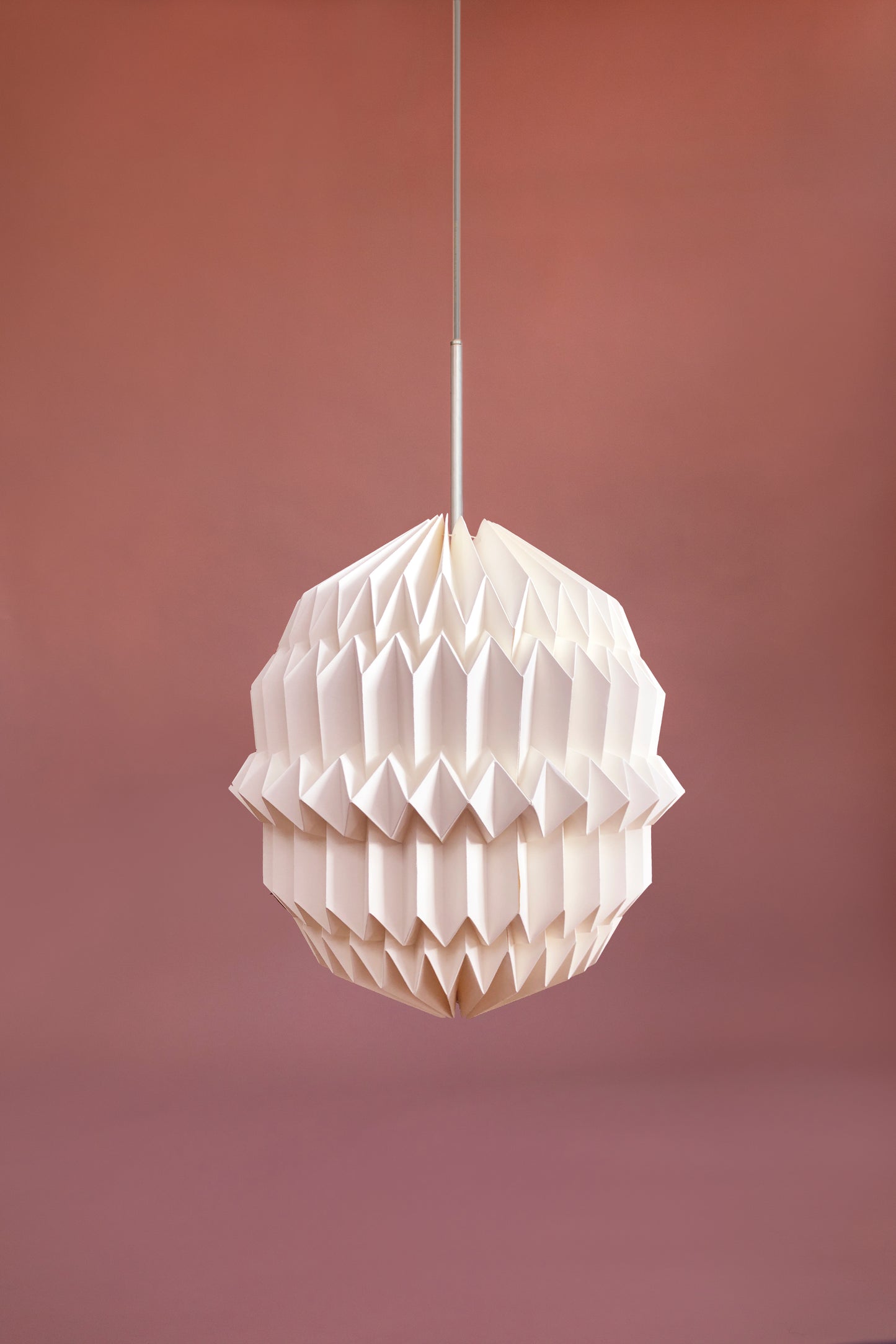 Plié Lights, lámpara colgante referencia Aries, hecha a mano, caperuza hecha en papel plegado a mano. Soporte metálica y cable transparente. Acabado blanco. Producto hecho en Colombia. Diseño Colombiano. igura geométrica muy interesante. Ideal para iluminar y darle calidez a los espacios.