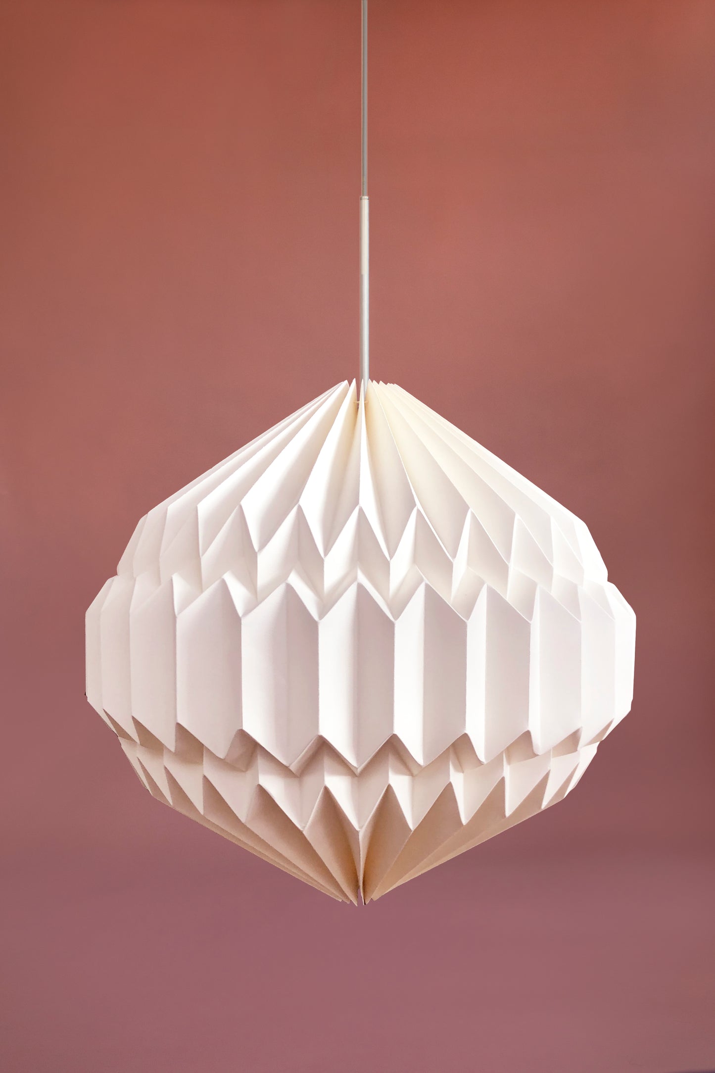 Plié Lights, lámpara colgante referencia luna, hecha a mano, caperuza hecha en papel plegado a mano. Soporte metálica y cable transparente. Acabado blanco. Producto hecho en Colombia. Diseño Colombiano. igura geométrica muy interesante. Ideal para iluminar y darle calidez a los espacios.