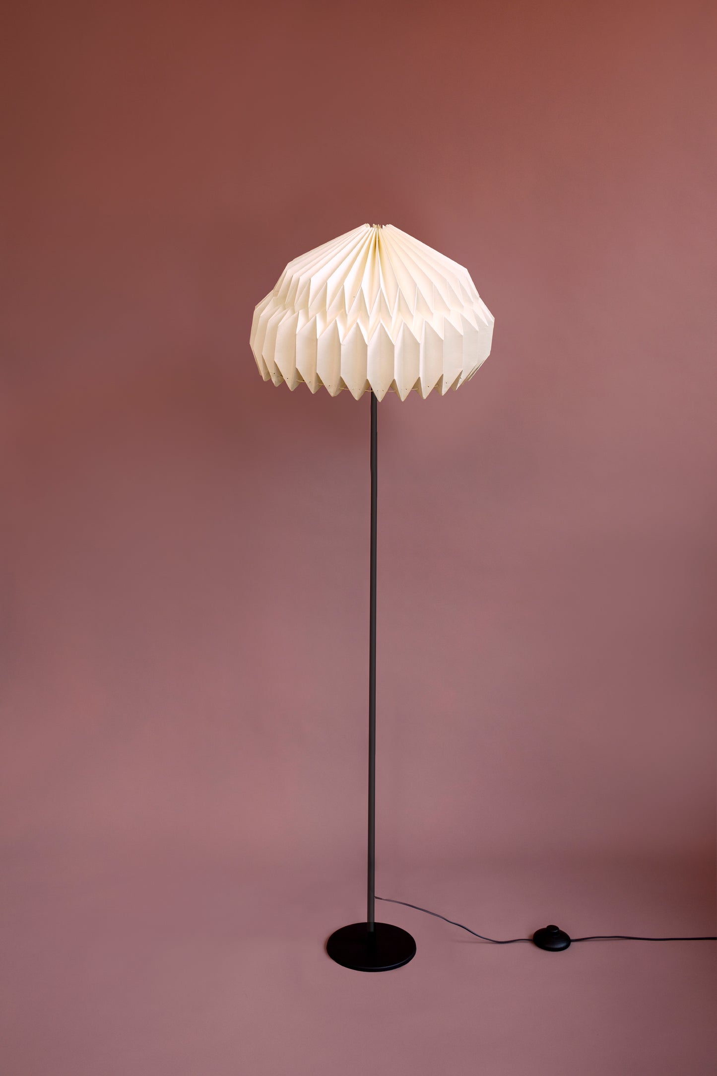 Lámpara de piso marca Plié referencia Alfa. Fabricada con base metálica y caperiza hecha en papel. Diseño colombiano hecho a mano. Acabado negro. Ideal para iluminar espacios cálidos. Figura geométrica.