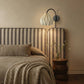 Plié Lights_Lámpara de pared ó aplique de pared referencia Gemini. Fotografía tomada en sitio de una habitación con una cama con cabecero en tela, el espacio está iluminado y la lámpara está apagada. Lámpara en papel con figura geometrica. 