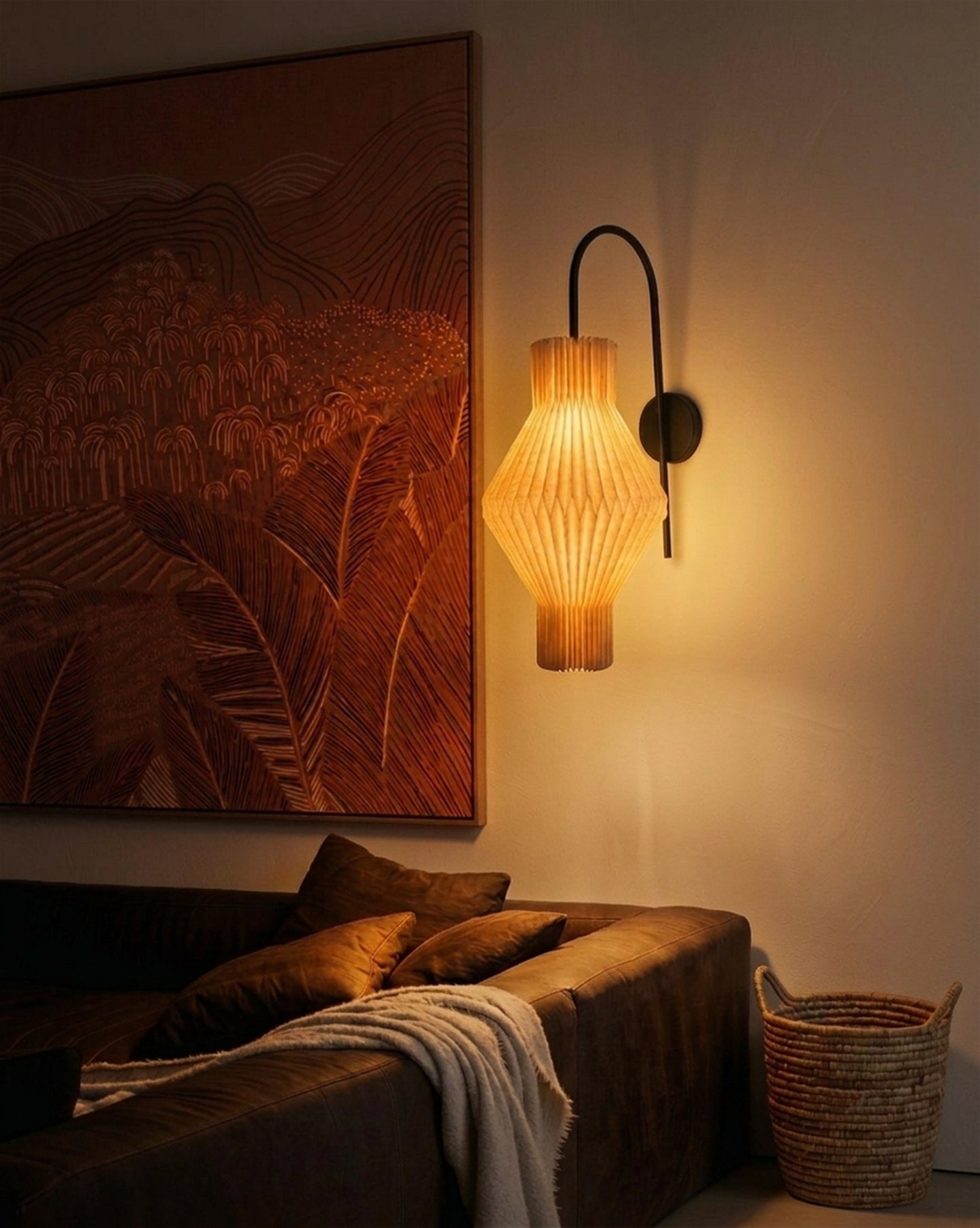 Plié Lights_Lampara de pared_aplique de pared_Fotografía de producto_Diseño geometrico_Hechas en papale doblada_con manos colombianas._Fotografía nocturna en sitio en una sala con una sofá y un cuadro. 