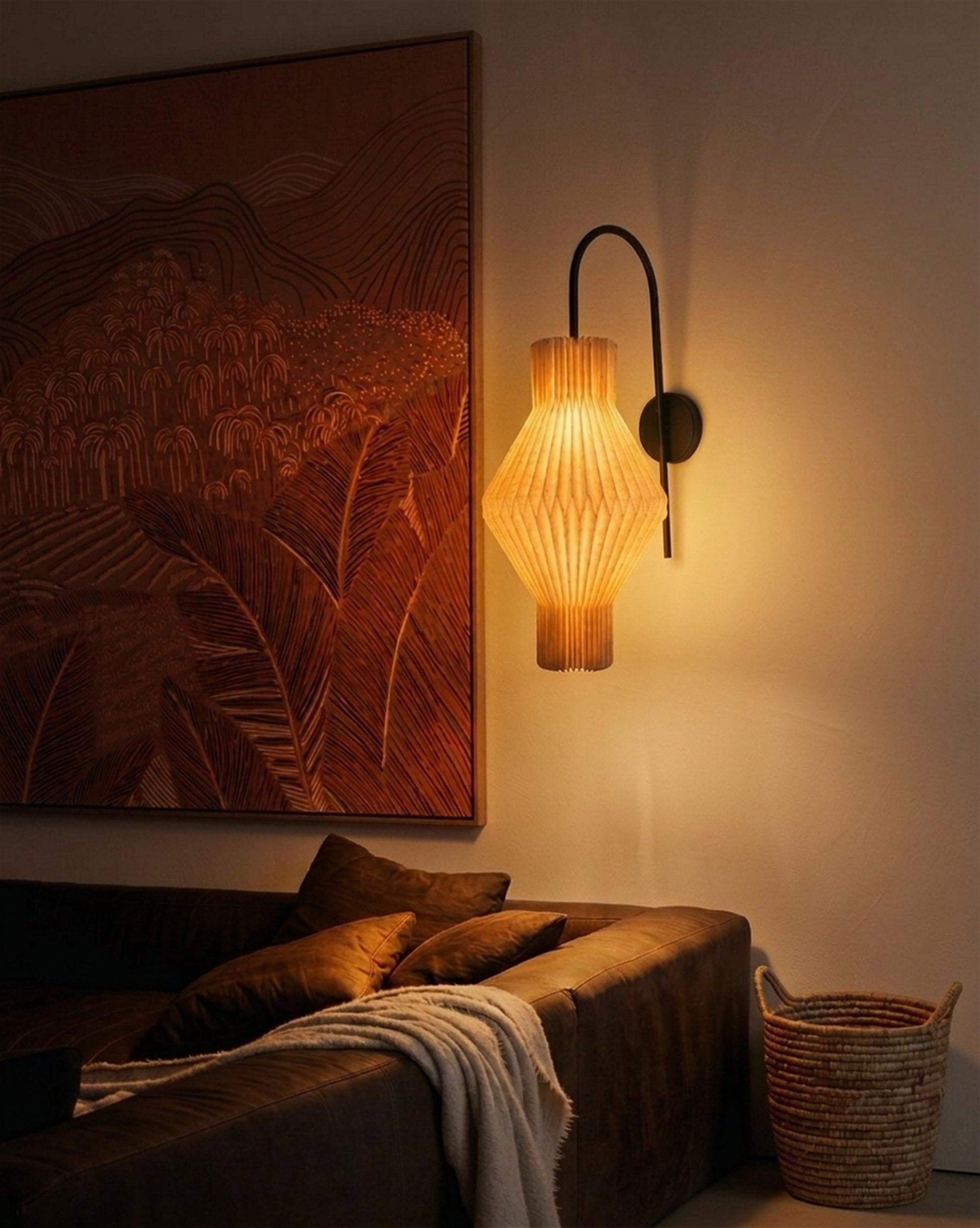 Plié Lights_Lampara de pared_aplique de pared_Fotografía de producto_Diseño geometrico_Hechas en papale doblada_con manos colombianas._Fotografía nocturna en sitio en una sala con una sofá y un cuadro. 