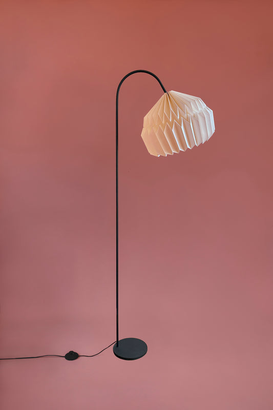 Plié Lights, lámpara de piso en forma de arco hecha en colombia. La base metálica tiene un tamaño perfecto para lámpara de lectura. La caperuza es referencia Alfa, tiene un diseño que genera luz directa hacia abajo. El diseño tiene pliegues en papel geométricos. Produce una iluminación cálida.