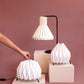 Tres lámpara de mesa fabricada con base metálica y caperuza hecha en papel plegado. Perfecta para iluminar espacios pequeños y dar un brillo a los espacios. Dos lámparas son pequeñas y la otra es tamaño mediano. 