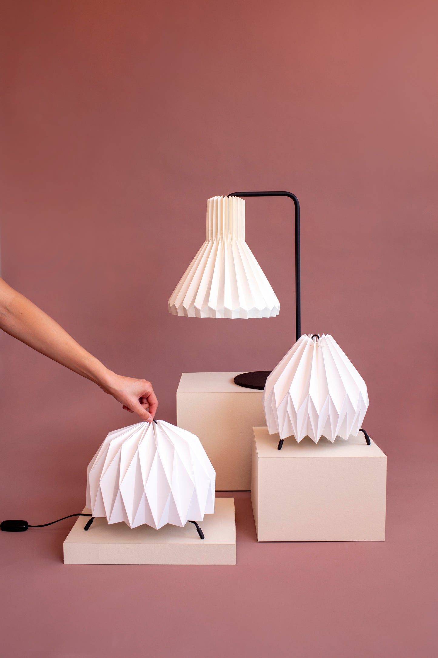 Tres lámpara de mesa fabricada con base metálica y caperuza hecha en papel plegado. Perfecta para iluminar espacios pequeños y dar un brillo a los espacios. Dos lámparas son pequeñas y la otra es tamaño mediano. 