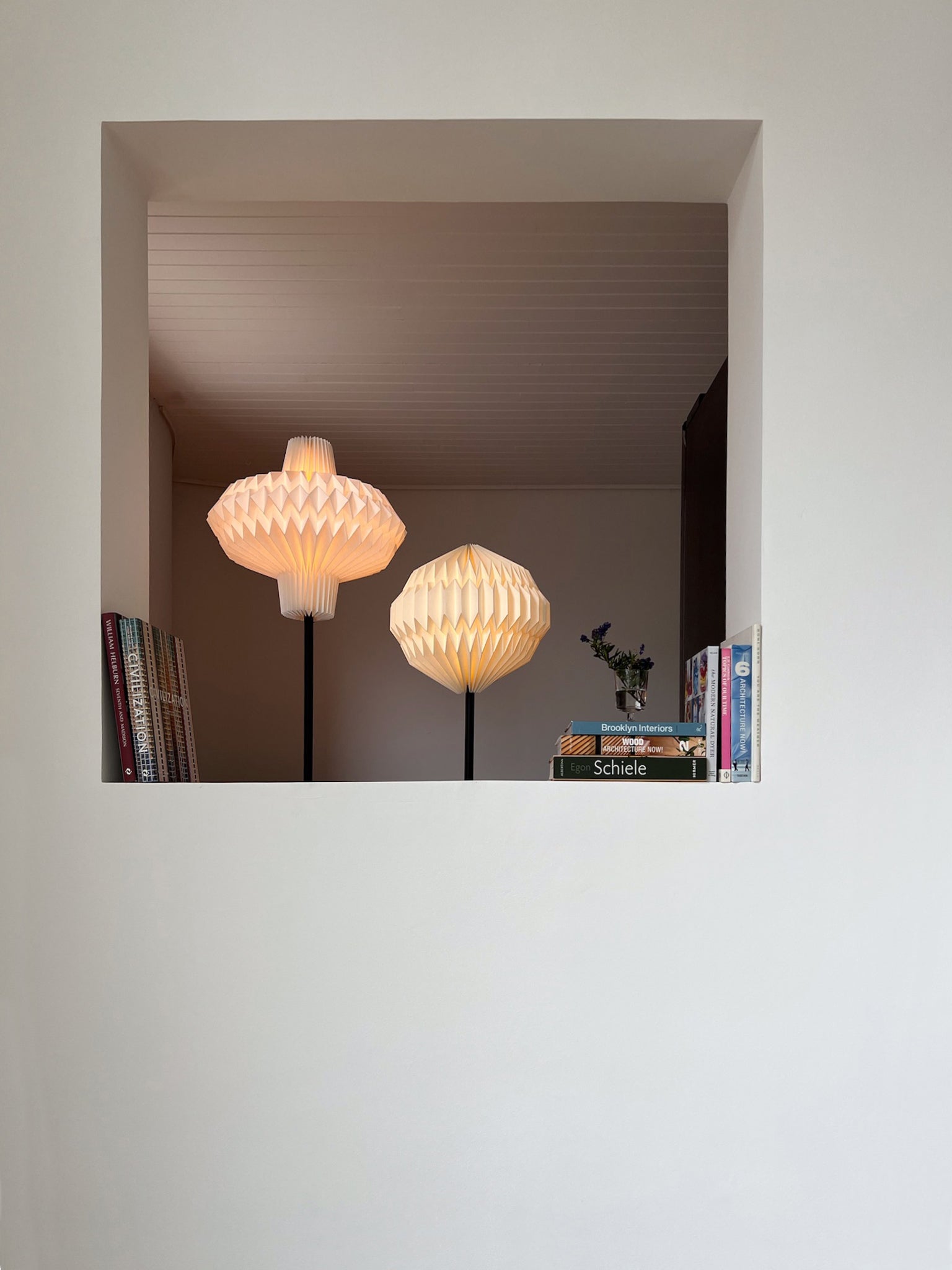 Lámpara de piso con caperuza redonda fabricada en papel al lado de otra lámpara de piso