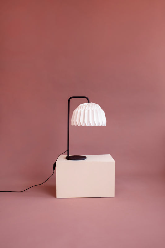 Lámpara Lyra de mesa fabricada con base metálica y caperuza hecha en papel plegado. Perfecta para iluminar espacios pequeños y dar un brillo a los espacios. Lámparas hechas en colombia.